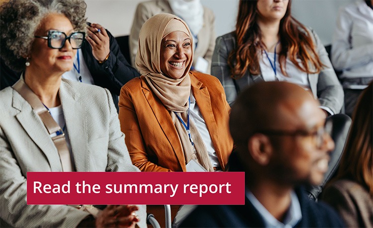 A group of people seated in an auditorium, all attentive and engaged. The background is blurred, highlighting the focus on the attendees.